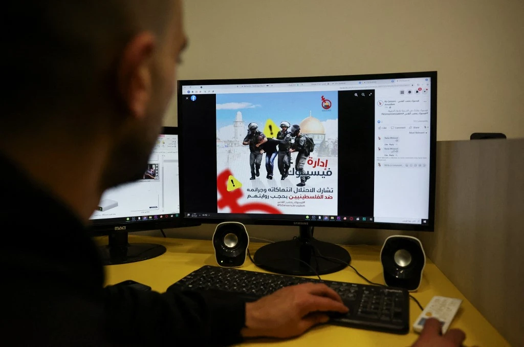 A Palestinian journalist shows the hashtag ‘#FBCensorsJerusalem’ of a campaign, created to protest against what journalists and activists consider censorship by Facebook of Palestinian content. (AFP)