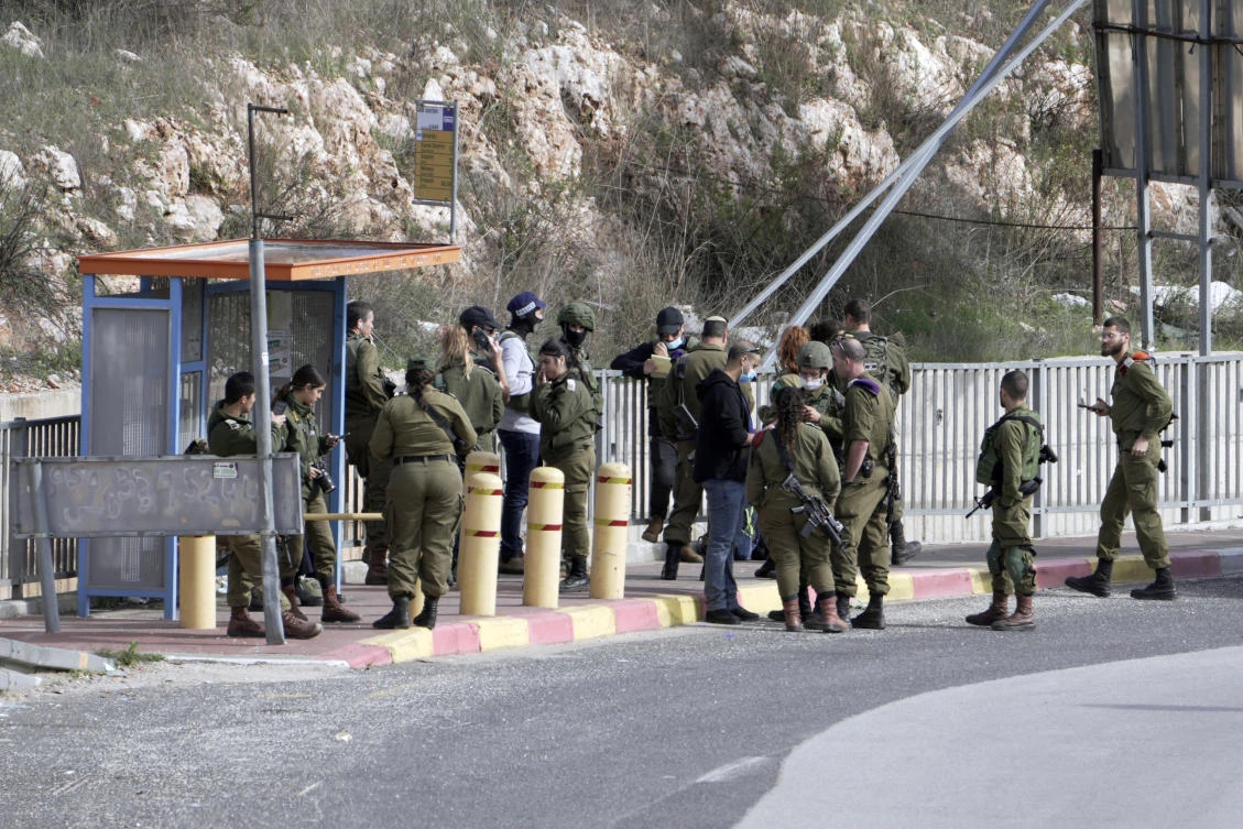 Israeli soldiers gather at a bus stop that was the site of an attempted stabbing attack at a junction near the settlement of Giti Avishar in the West Bank on Dec. 31, 2021. (AP)