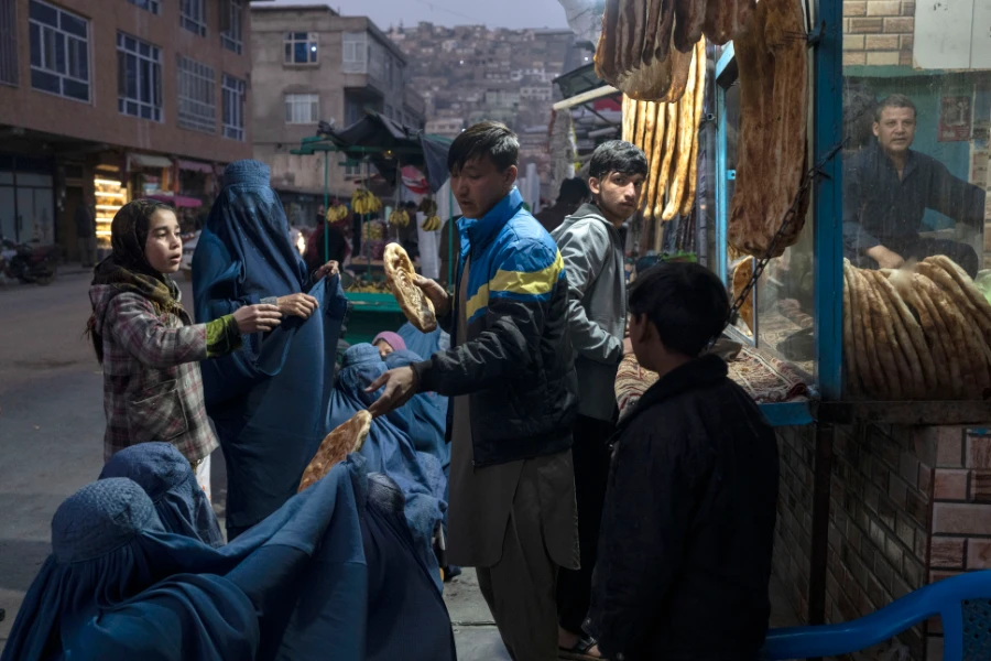 A man distributes bread to Burka-wearing Afghan women outside a bakery in Kabul, Afghanistan, Thursday, Dec, 2, 2021. (AP)