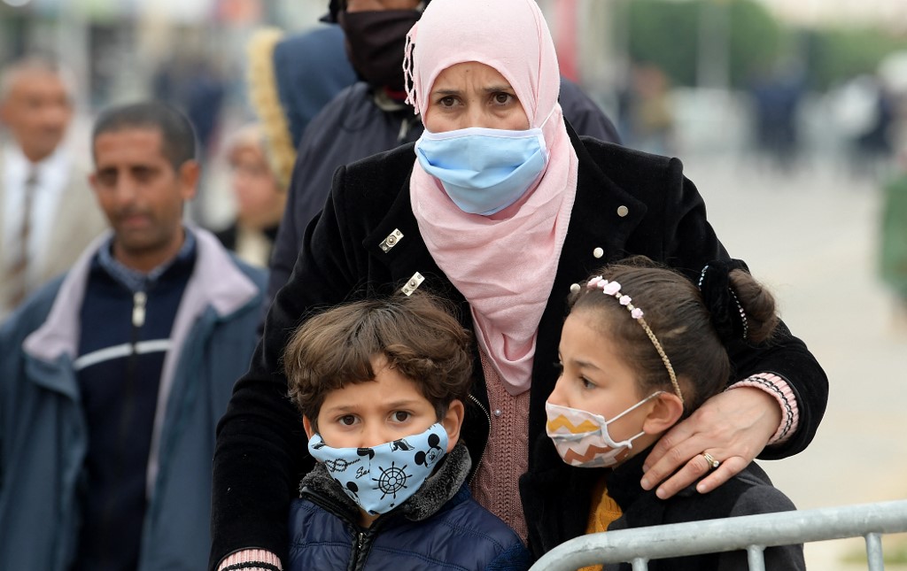 A woman and children, clad in masks due to the COVID-19 coronavirus pandemic, gather in Mohamed Bouazizi Square in central Tunisia. (File/AFP)