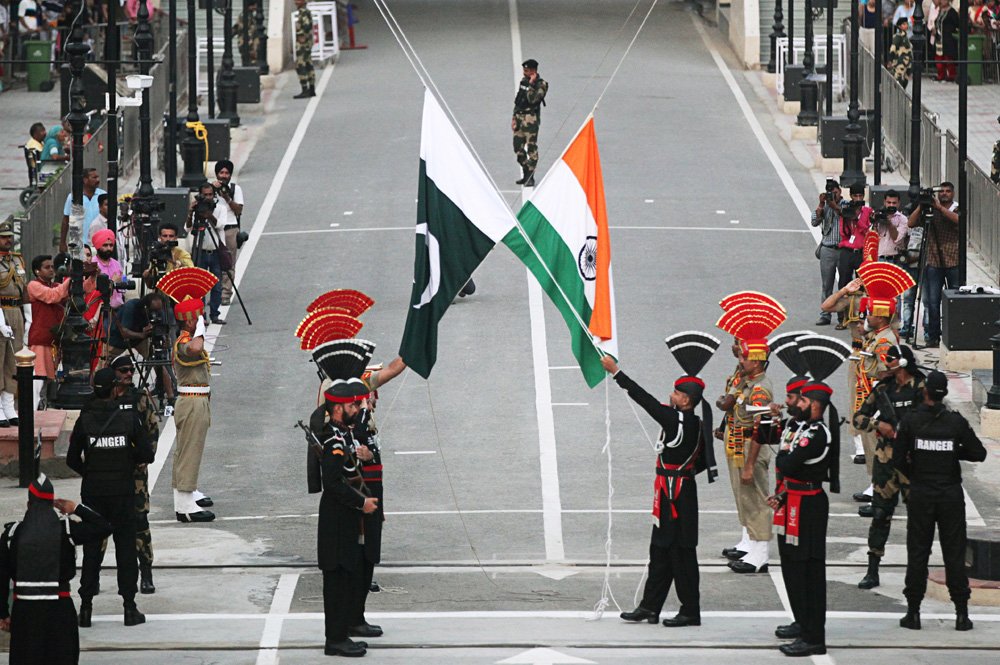 Pakistani Rangers and Indian BSF officers lower their national flags during the Wagah-Attari border ceremony, Aug. 14, 2019. (Reuters)
