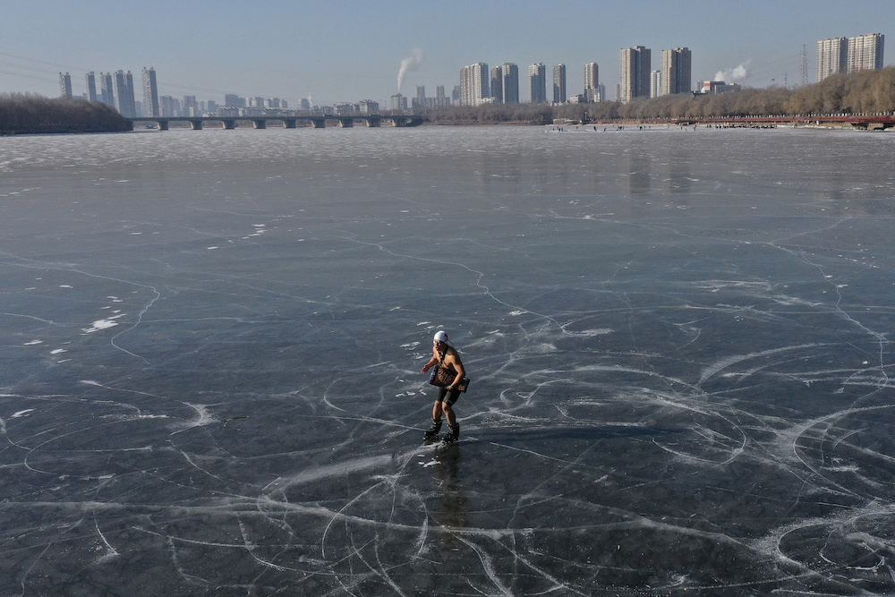 A winter swimming enthusiast skates on a frozen lake in Shenyang, in northeastern China's Liaoning province on December 31, 2021. (AFP)