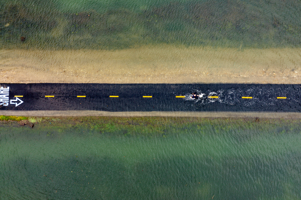 An aerial picture taken on January 3, 2022, a man running along a flooded Sausalito/Mill Valley bike path during the "King Tide" in Mill Valley, California. (AFP)