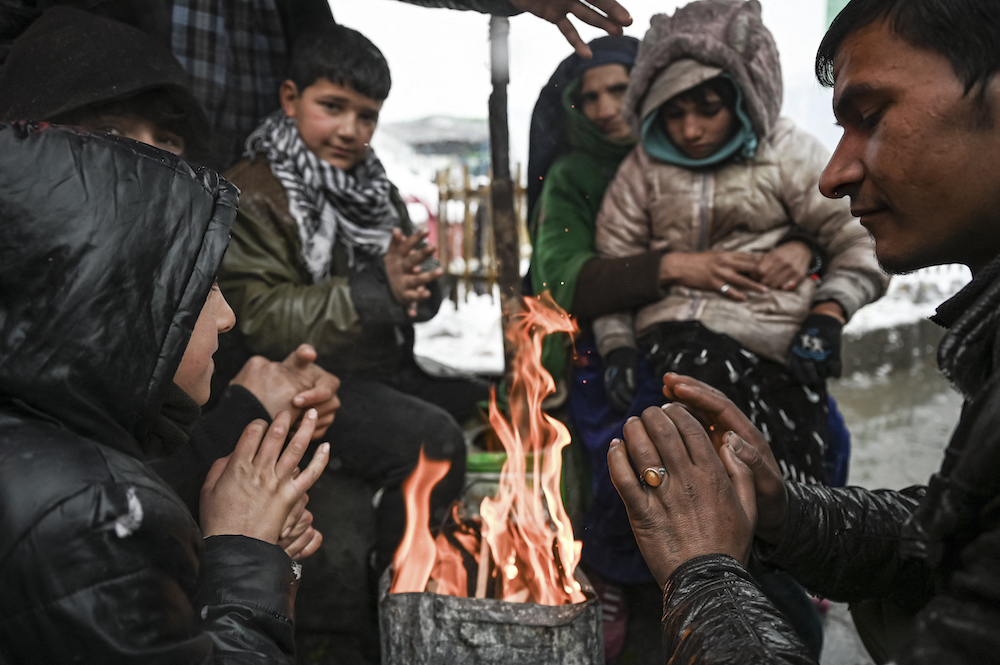 People warm up around a bonfire during heavy snowfall in Kabul on January 4, 2022. (AFP)