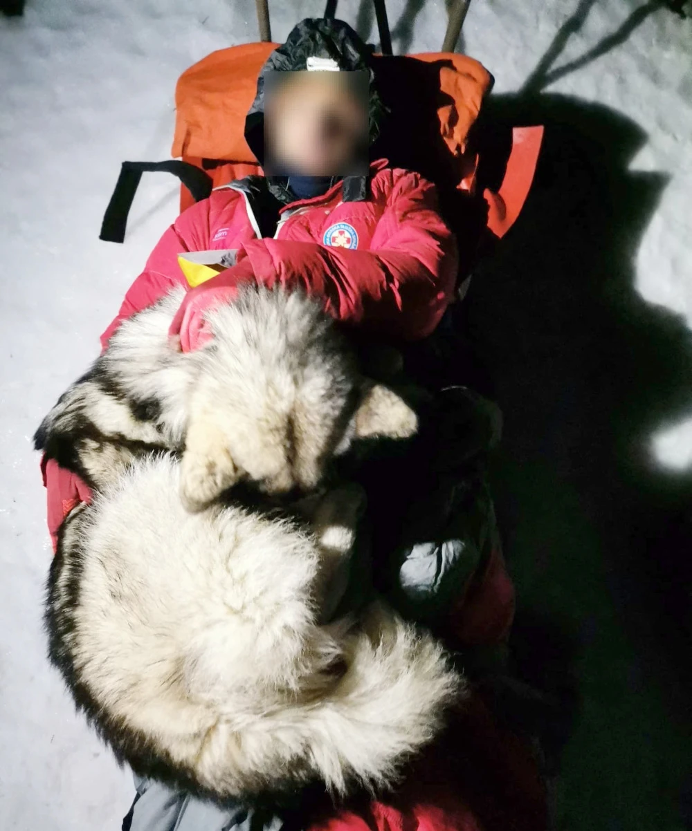 This undated photograph released by Croatian Mountain Rescue Service (HGSS) on January 4, 2022, shows the dog "North" lying on a mountaineer as they are rescued by HGSS servicemen on the mountain of Velebit. (AFP)