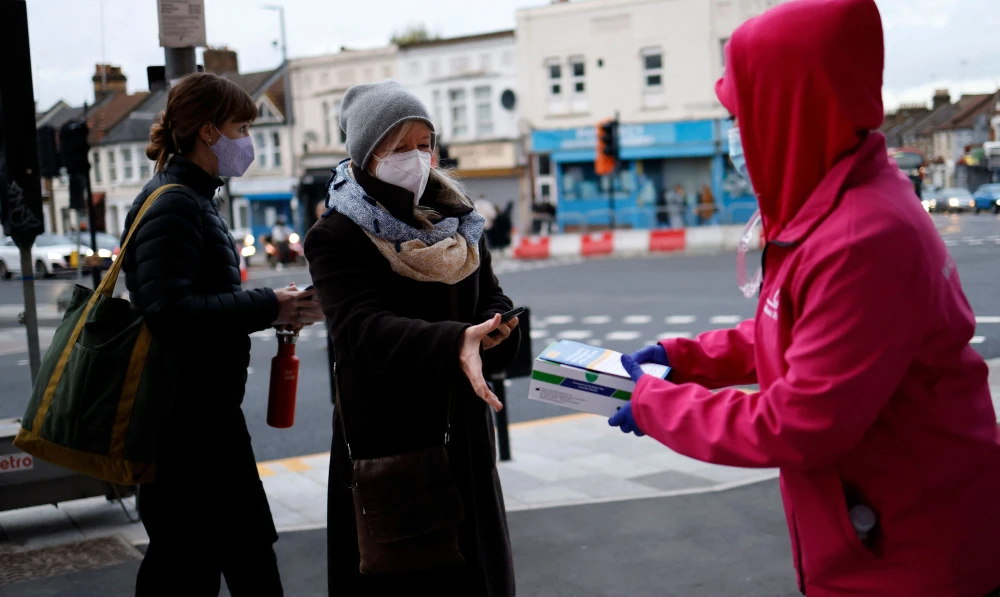 Volunteers hand out boxes of Covid-19 rapid antigen Lateral Flow Tests (LFT), in north east London on January 3, 2022. (AFP)