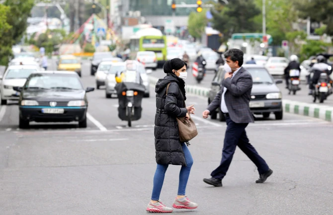 Iranians cross a main road in Tehran, where dissident poet and filmmaker Baktash Abtin died on Saturday in detention after falling ill with Covid-19. (AFP)