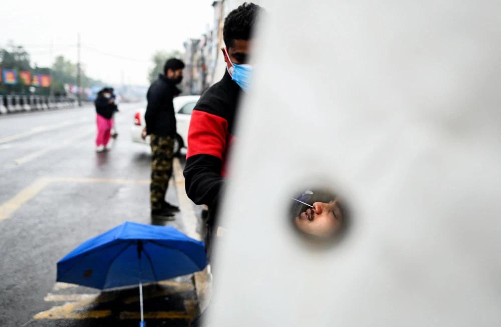 A health worker performs a Covid-19 coronavirus screening along a partially deserted street at a market area in New Delhi on January 8, 2022. (AFP)