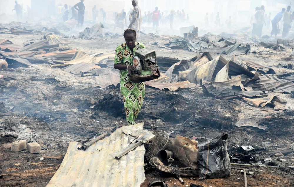 A local resident attempts to salvage a stove from the fire in the biggest Lagos wood market, Oko-Baba Sawmill, in Ebute-Metta, district of Lagos, on January 5, 2022. (AFP)