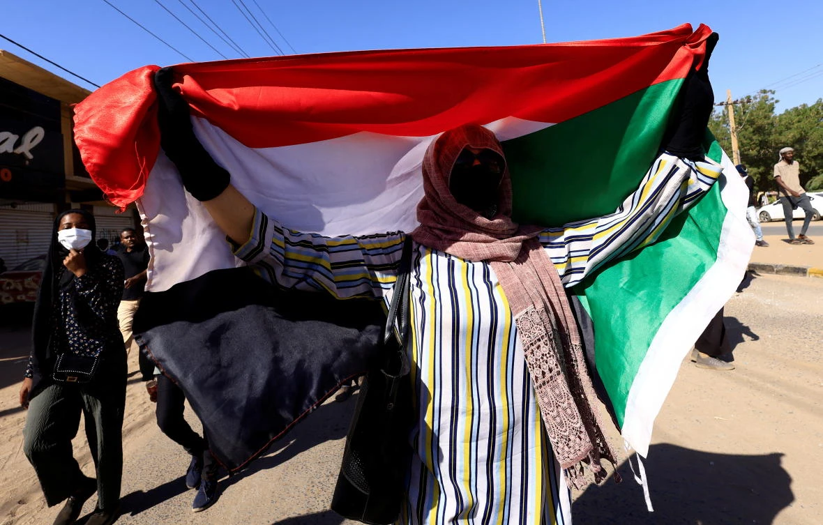 A person holds up Sudan's flag as protesters march during a rally against military rule in Khartoum, Sudan, January 6, 2022. (Reuters)