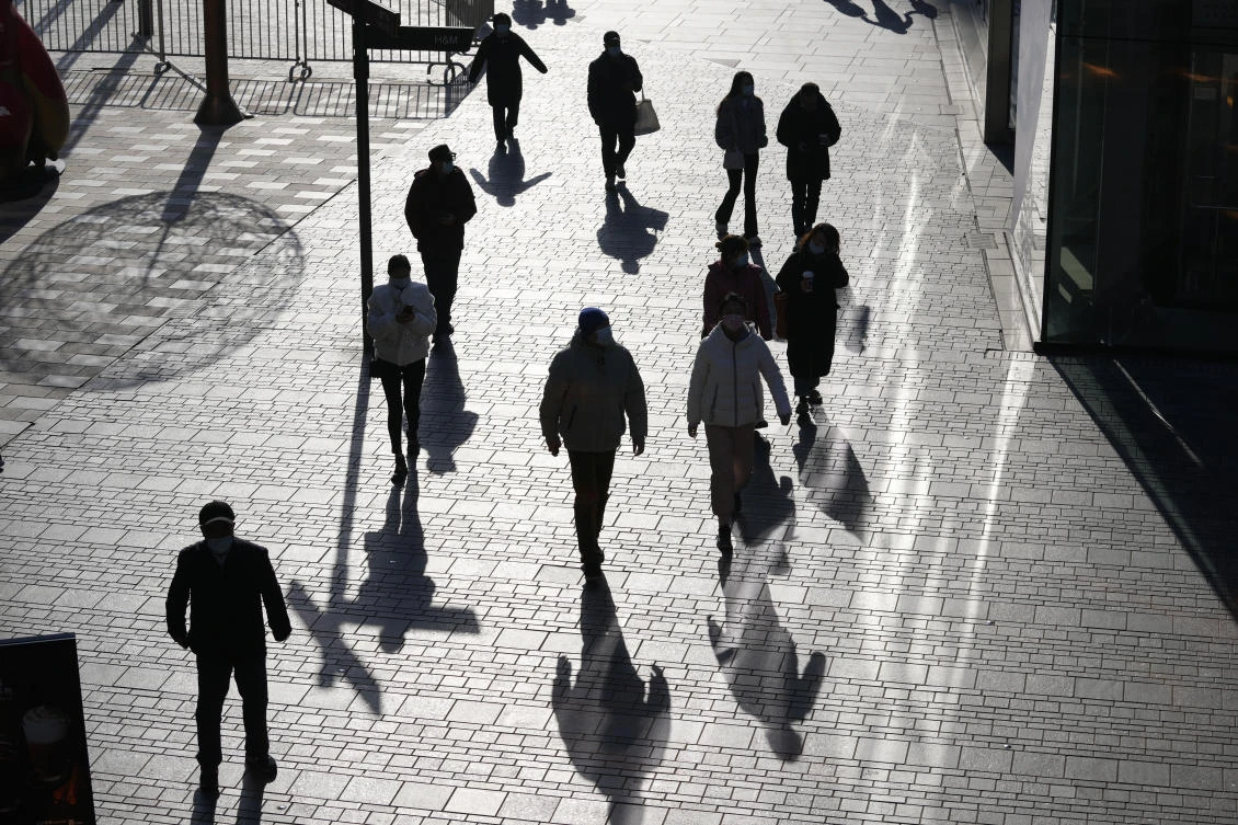 Visitors to a shopping mall cast shadows as they walk through a health check point in Beijing, China, on Dec. 14, 2021. (File/AP)
