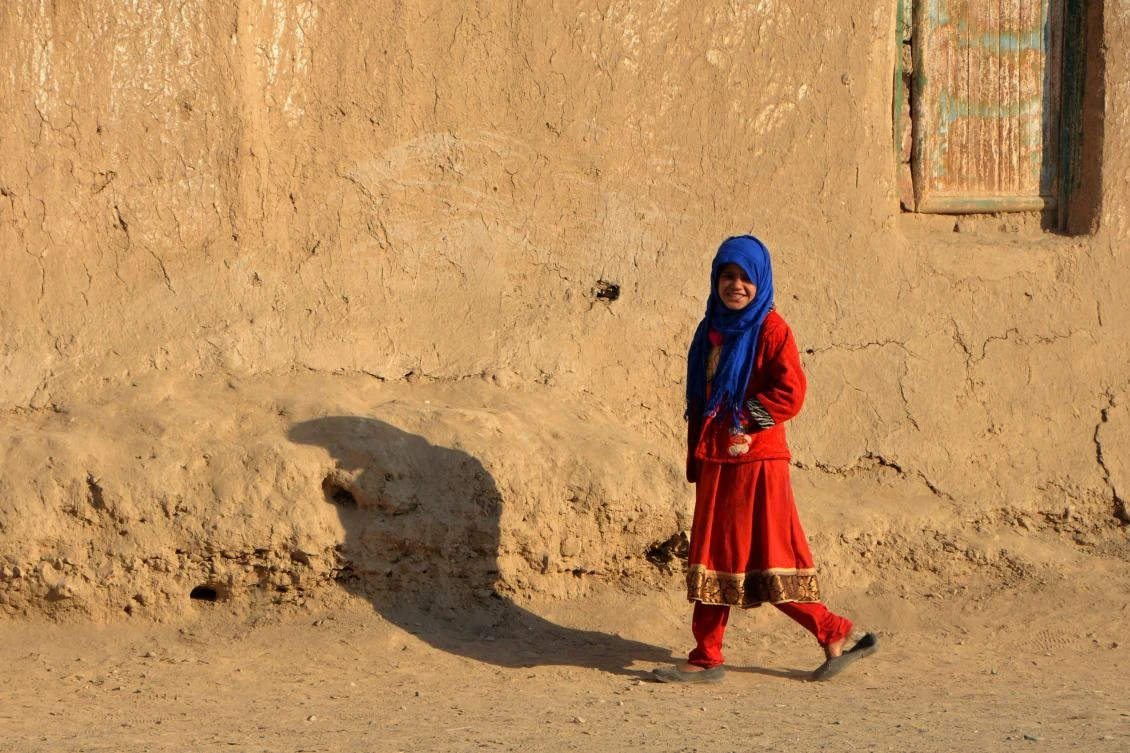 An Afghan girl walks past a mud house in Kandahar city on January 8, 2022. (AFP)