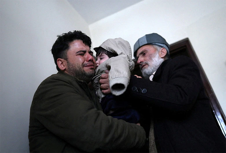 Hamid Safi, a 29-year-old taxi driver who had found baby Sohail Ahmadi in the airport, cries as he hands over Sohail to his grandfather Mohammad Qasem Razawi in Kabul, Afghanistan, January 8, 2022. (REUTERS)