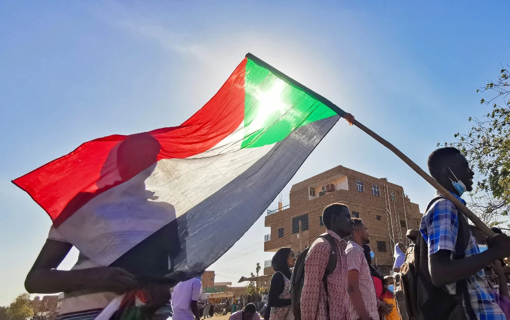 A Sudanese man carries a national flag during a protest against the October 2021 military coup, in the capital Khartoum, on January 9, 2022. (AFP)
