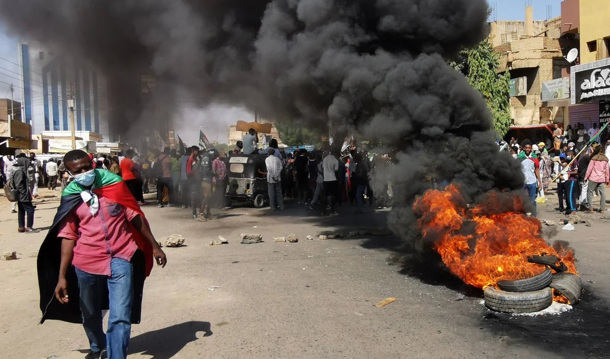 Sudanese protesters walk past burning tyres as they rally to protest against the October 2021 military coup, in the capital Khartoum, on January 9, 2022. (AFP/File)