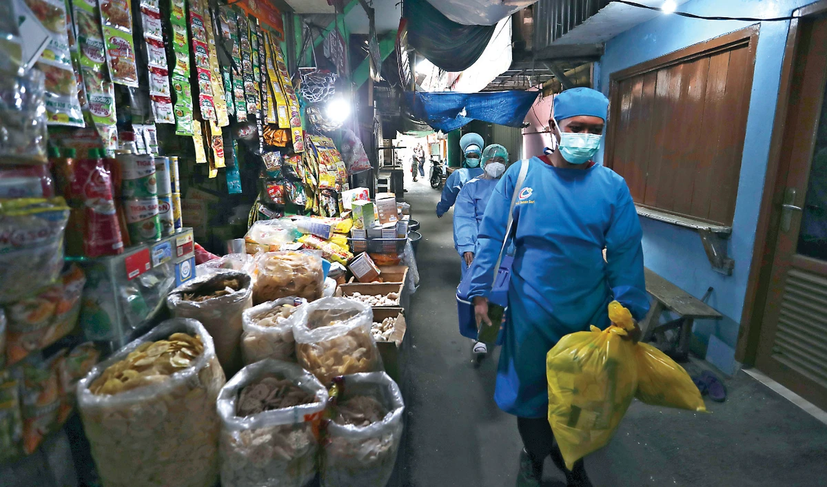 Health workers walk through a market as they conduct mass coronavirus tests in Jakarta. The COVID-19 vaccine will be provided free for all citizens. (AP)