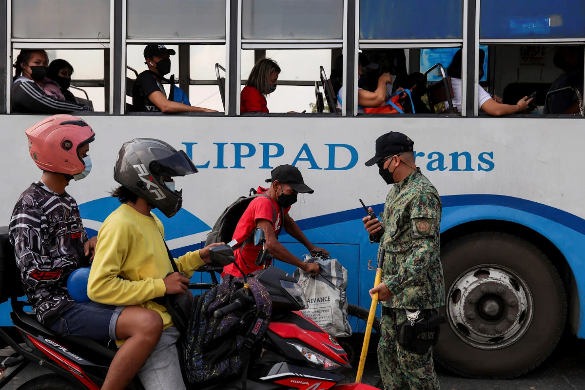 A Philippine police officer checks passers-by for vaccination documents in Manila on Jan. 10, 2021. (AP Photo/Basilio Sepe)