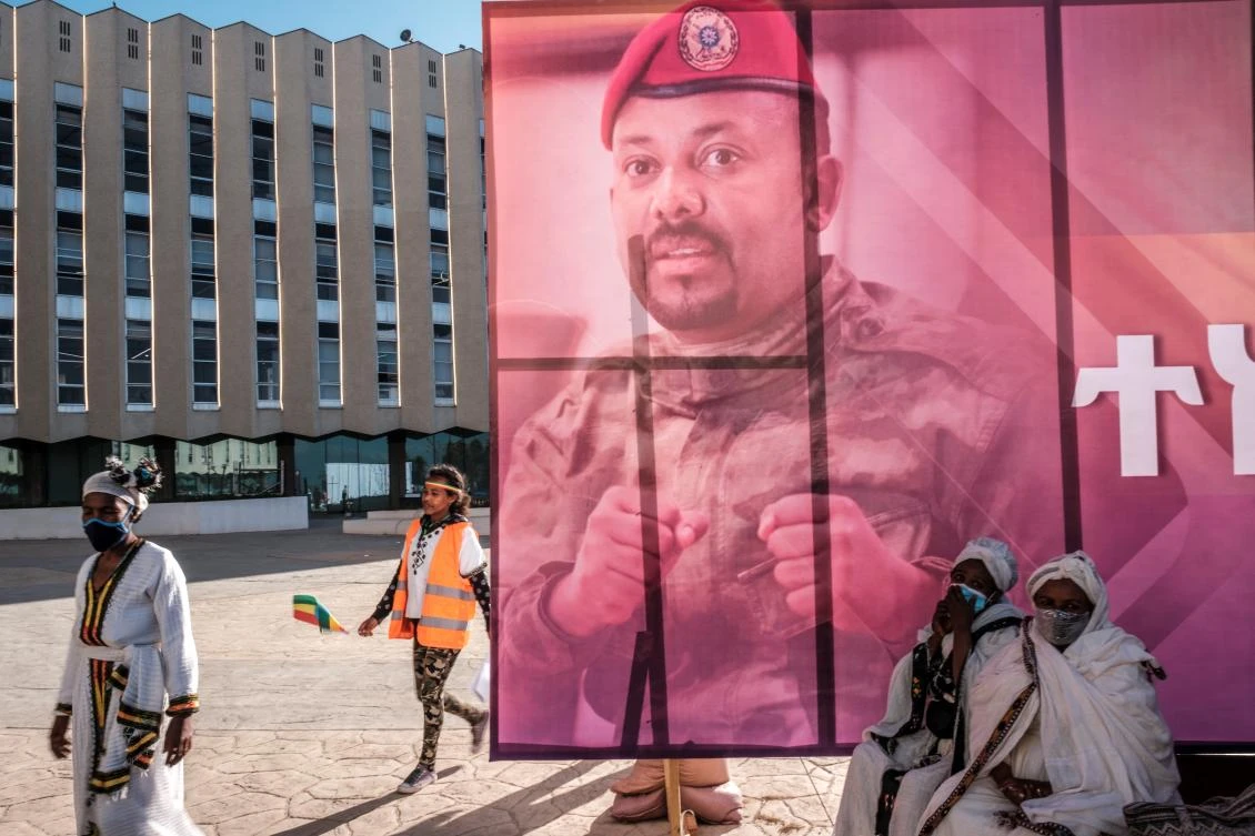 People walk next to a banner depicting Ethiopia's Prime Minister Abiy Ahmed during a rally organized by Addis Ababa officials. (File/AFP)