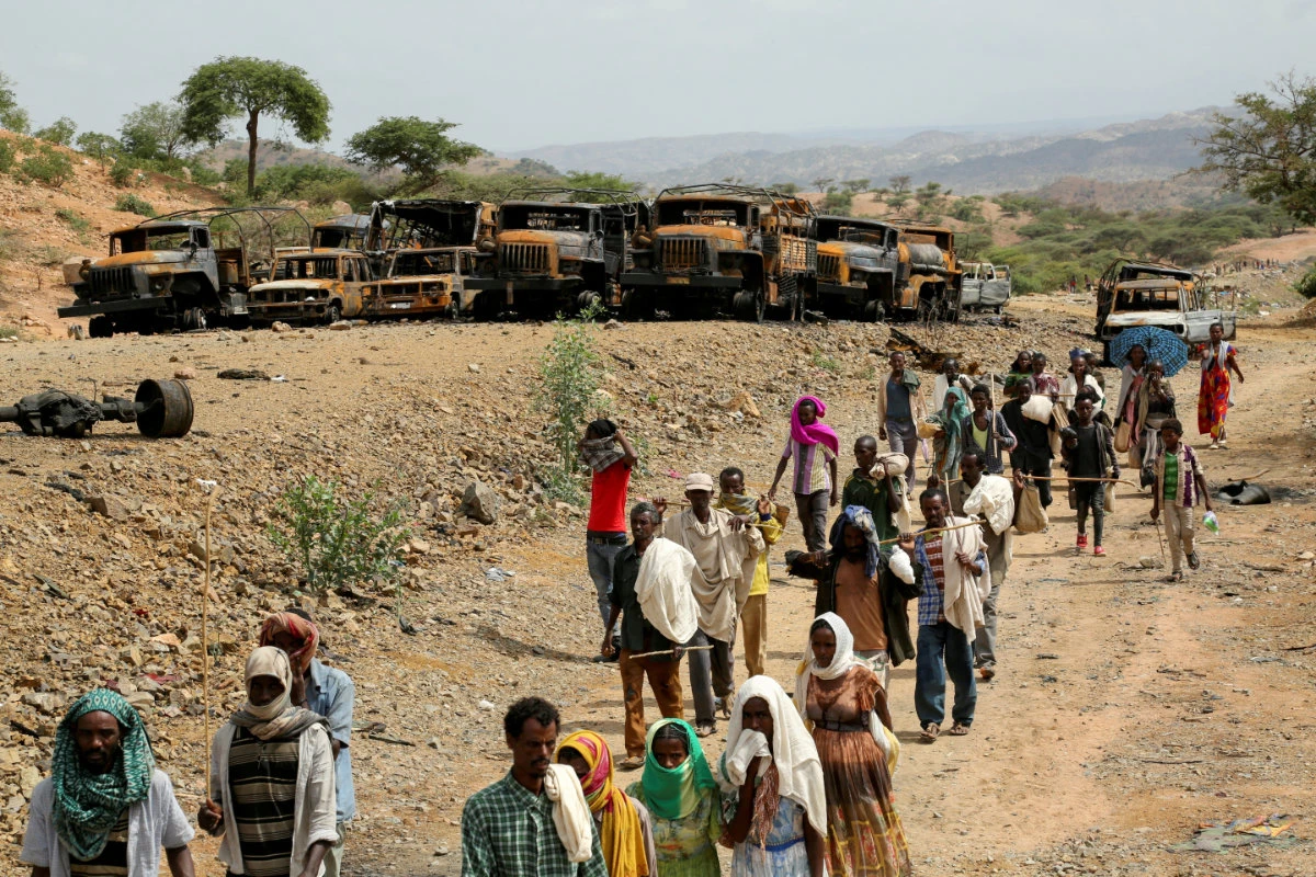 Villagers walk past burned vehicles in an air strike as they return to Yechila town in south central Tigray on July 10, 2021. (REUTERS/Giulia Paravicini/File)