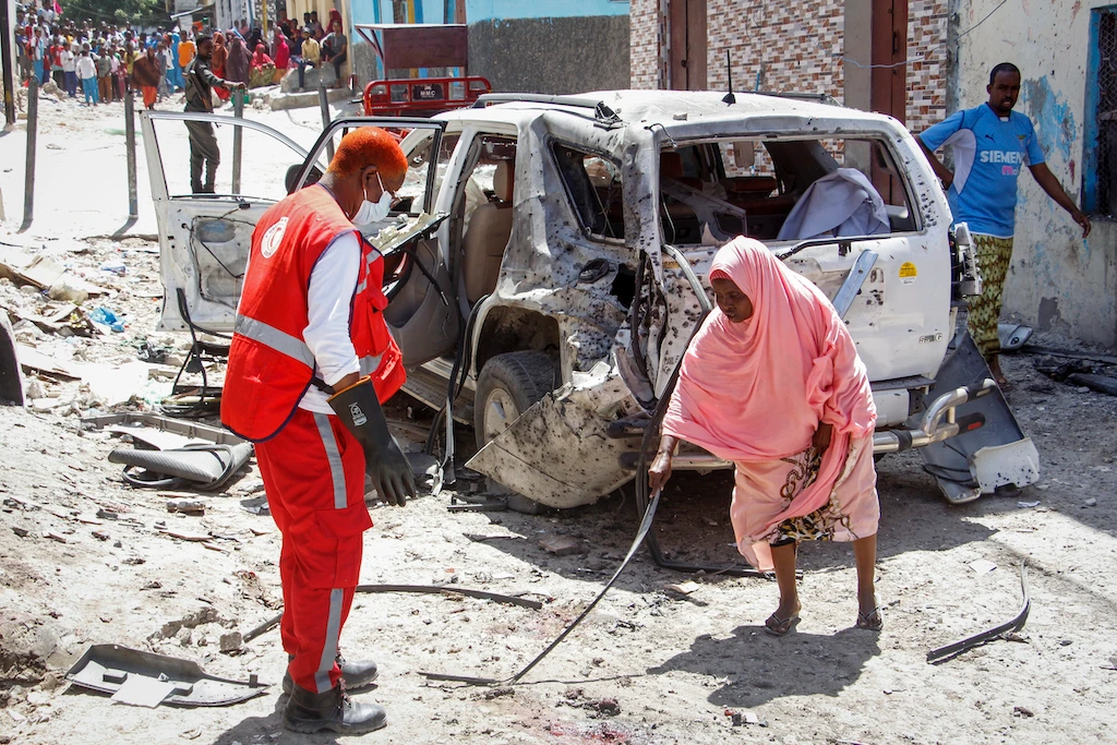 A woman, right, points a medical worker to remains of the suicide bomber at the scene, after Somalia's government spokesperson Mohamed Ibrahim Moalimuu was wounded in a suicide bombing in Mogadishu, Somalia, Sunday, Jan. 16, 2022. (AP)