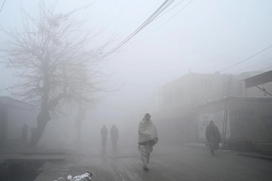 People walk along a road during a foggy day in Kabul on January 18, 2022. (AFP)