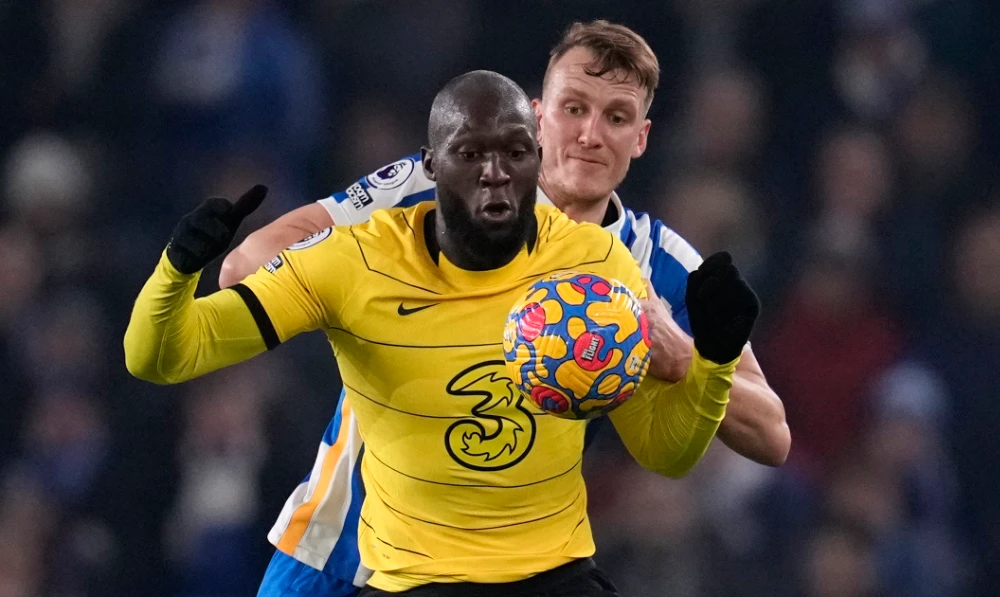 Chelsea's Romelu Lukaku, front, duels for the ball with Brighton's Dan Burn during the English Premier League soccer match between Brighton and Chelsea in Brighton, England, Tuesday, Jan. 18, 2022. (AP)