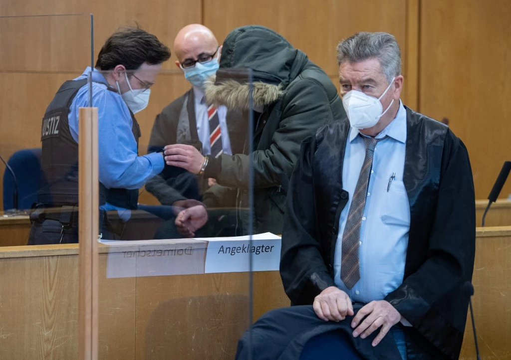 Defendant Alaa M., second right, has his handcuffs taken off and stands next to his lawyers as he arrives on Jan.y 19, 2022 at court in Frankfurt for the start of his trial. (AFP)