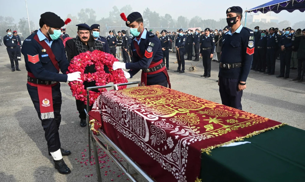 Pakistan's Interior Minister Sheikh Rashid Ahmed, second left, places a wreath of flowers on the coffin of a police officer, who was killed in an overnight gunmen attack, during the funeral ceremony on Tuesday. (AFP)