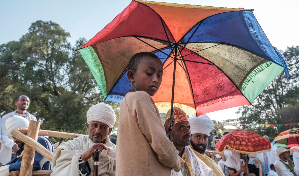 An Ethiopian Orthodox child holds un umbrella during the celebration of the eve of Timkat, the Ethiopian Epiphany, in the city of Gondar, Ethiopia, on January 18, 2022. (AFP)