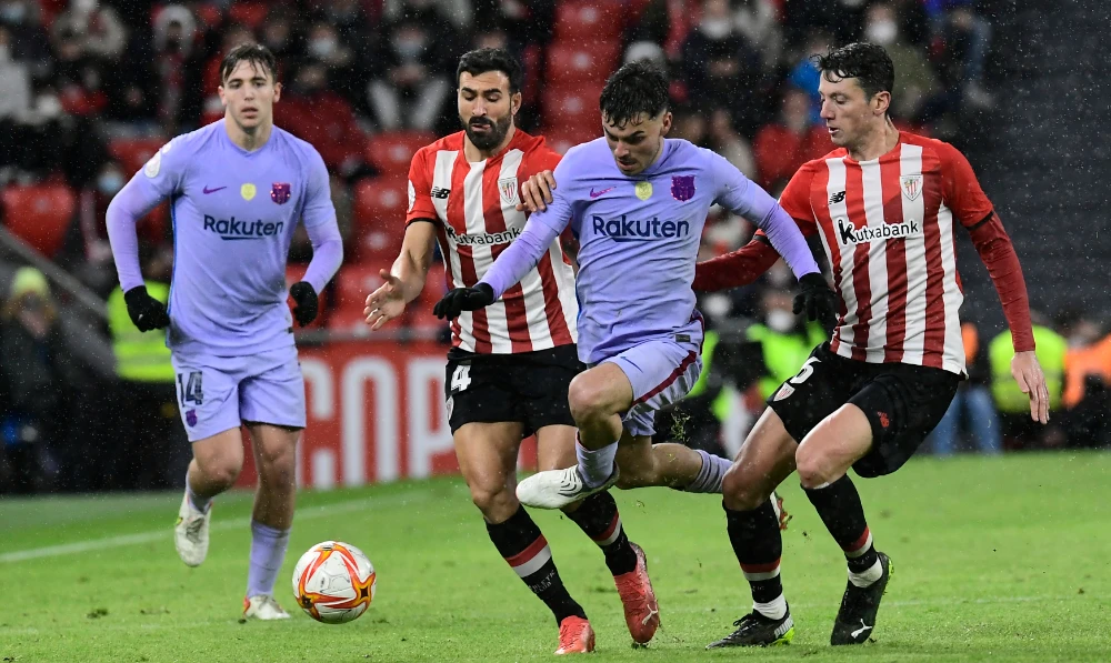 Barcelona's Pedri, center, is challenged by Athletic Bilbao's Mikel Vesga, right and Athletic Bilbao's Inigo Martinez during the Spanish Copa del Rey Cup round of 16 soccer match at the San Mames stadium in Bilbao, Friday. (AP)