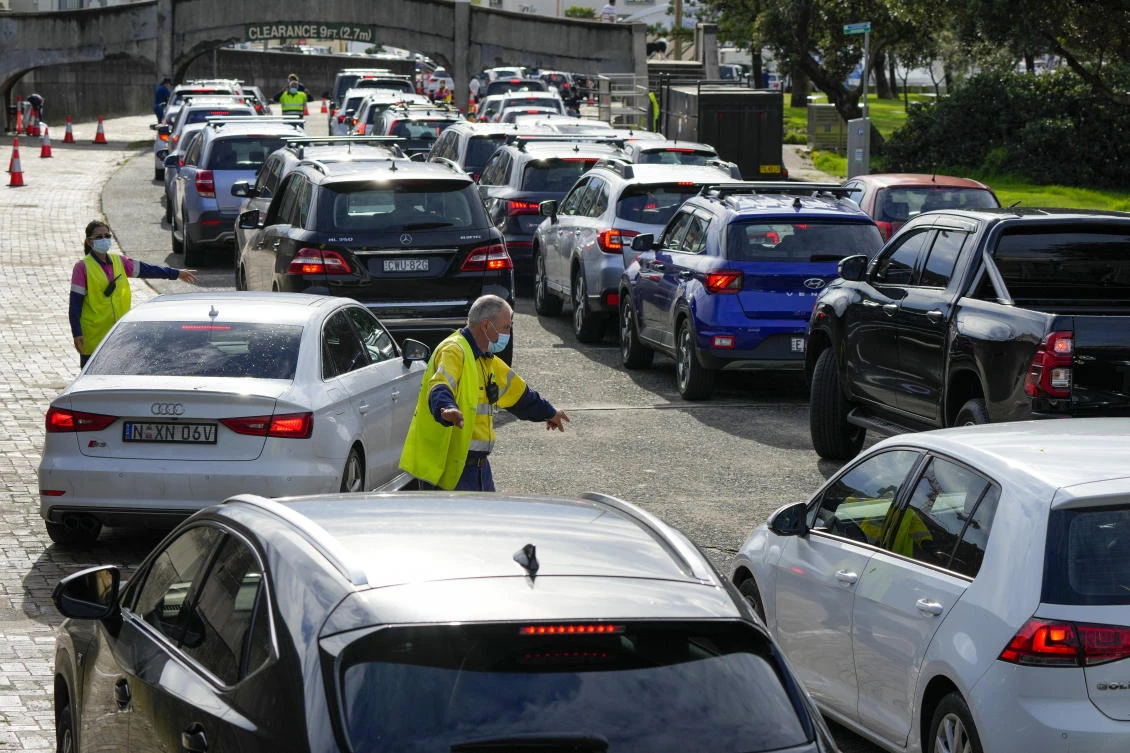 Above, traffic marshals direct vehicles at a drive-thru COVID-19 testing clinic at Bondi Beach in Sydney, Australia. (AP)