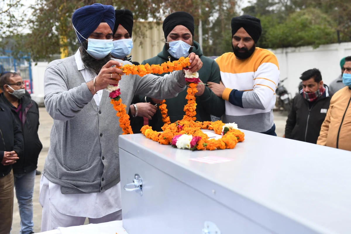 Relatives pay tribute in front of the coffin of Hardeep Singh, who was killed on the January 17 drone attack in Abu Dhabi, at the Sri Guru Ram Dass Jee International Airport on the outskirts of Amritsar on January 21, 2022. (AFP)