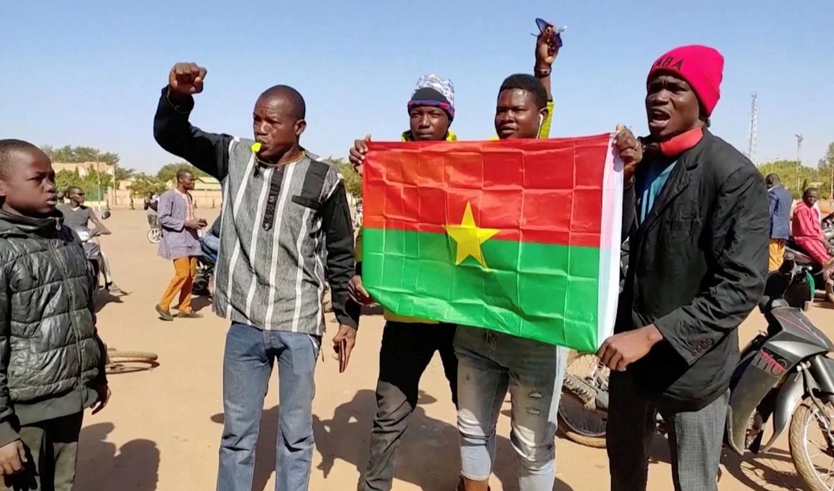 People hold a Burkina Faso flag as hundreds gather in downtown Ouagadougou to show support for the military, in Burkina Faso, in this still image taken from video on January 23, 2022. (Reuters)
