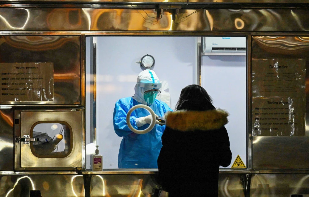 A health worker prepares to collect swab samples to test for the Covid-19 coronavirus from a participant of the Beijing 2022 Olympic Games at the parking lot of a hotel in Beijing on January 25, 2022. (AFP)
