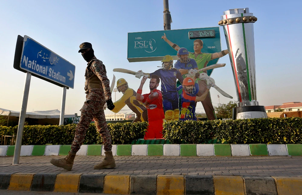 A paramilitary soldier patrols next to cricket player cutouts, outside the National Stadium, ahead of the Pakistan Super League opener, Karachi, Pakistan, Jan. 25, 2022. (AP Photo)
