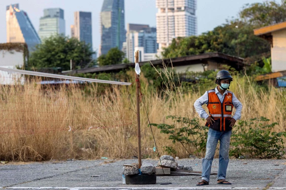 A motorbike taxi driver looks on from the sidelines as men play a game of sepak takraw in Bangkok on January 25, 2022. (AFP)