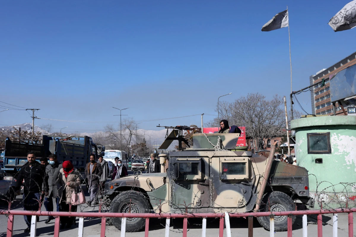 Afghans walk past a Humvee with a Taliban fighter on it guarding the road in Kabul on Jan. 27, 2022. (REUTERS/Ali Khara)