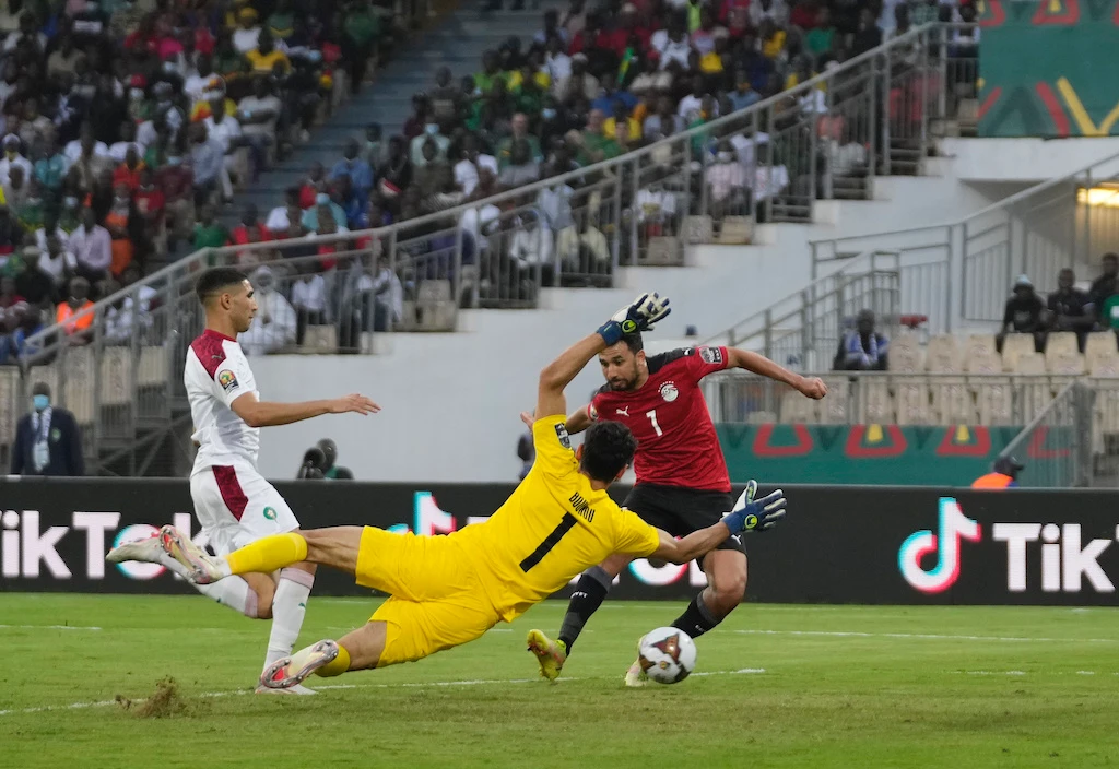 Egypt's Mahmoud Hassan Trezeguet, right, scores a goal past Morocco's goalkeeper Yassine Bounou, foreground, during the AFC 2022 quarter-final soccer match between Egypt and Morocco, Jan. 30, 2022. (AP)