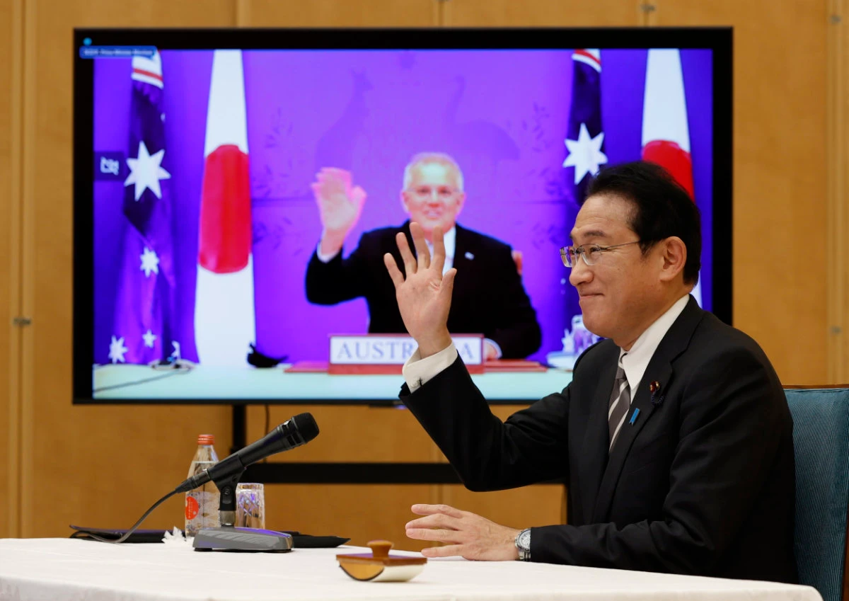 Japan's PM Fumio Kishida, right, and Australia's PM Scott Morrison seen on screen, attend a virtual summit to sign the Reciprocal Access Agreement on Jan. 6, 2022. (Issei Kato/Pool Photo via AP)