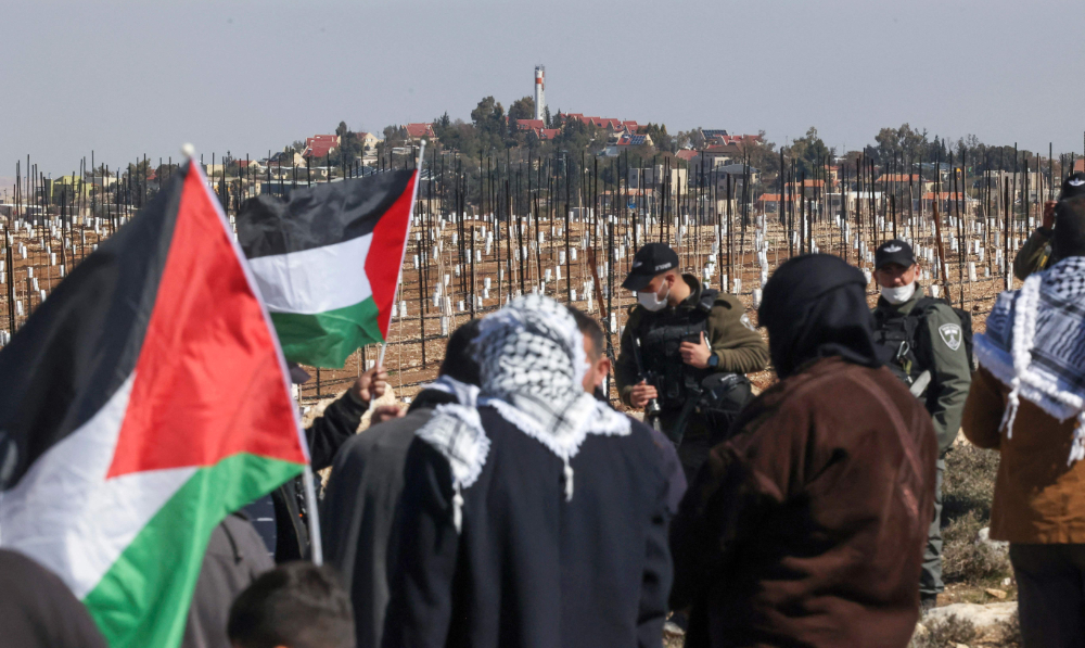Israeli security officers deploy as Palestinian landowners demonstrate next to land confiscated for the Israeli settlement of Karmel (background), near Yatta village south of Hebron city in the occupied West Bank, on Feb. 12, 2022. (AFP)