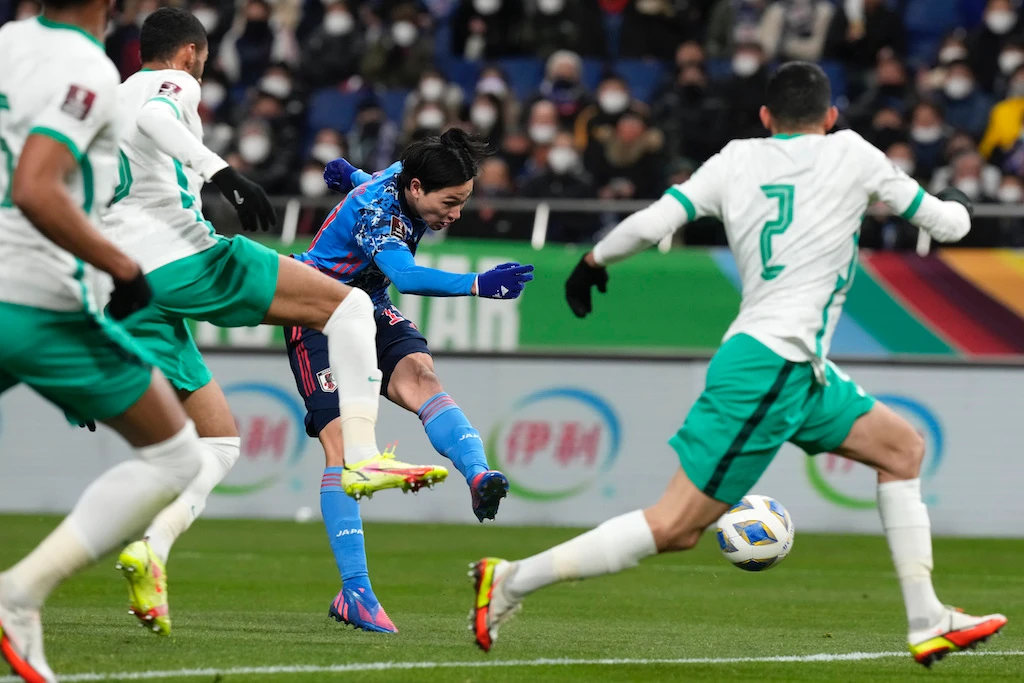 Japan's Takumi Minamino, center, shoots to score a goal during the World Cup 2022 group B qualifying soccer match between Japan and Saudi Arabia at Saitama Stadium 2002 in Saitama, north of Tokyo, Tuesday, Feb. 1, 2022. (AP)