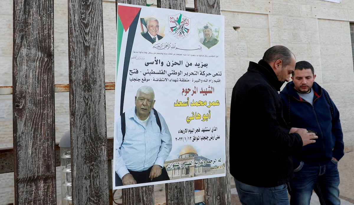 Men stand next to a poster of Palestinian Omar Abdalmajeed As'ad, in Jiljilya village in the Israeli-occupied West Bank, January 12, 2022. (Reuters)
