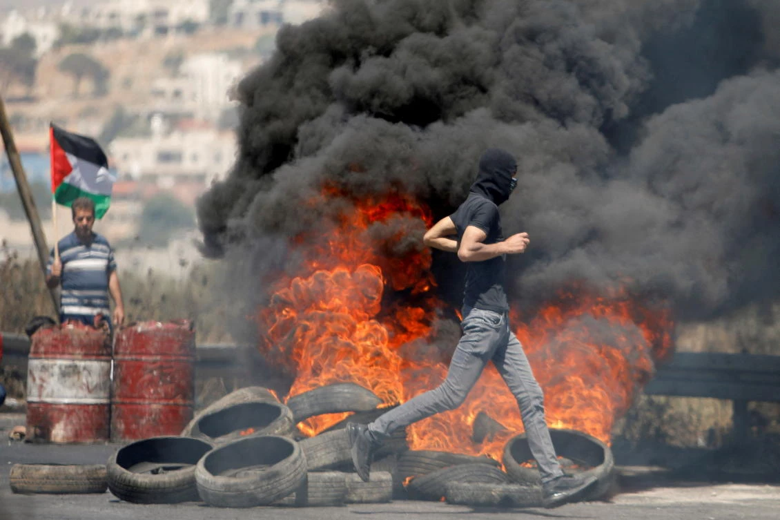 FILE PHOTO: A Palestinian demonstrator runs past burning tires during a protest over tension in Jerusalem and Israel-Gaza escalation, near Nablus in the West Bank in May 2021. (Reuters)