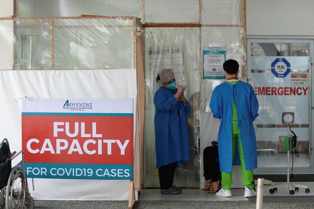 Health workers assess a patient at the Adventist Medical Center, where a sign indicating that the hospital’s COVID-19 facility is at full capacity, Pasay, Philippines, Apr. 9, 2021. (Reuters)