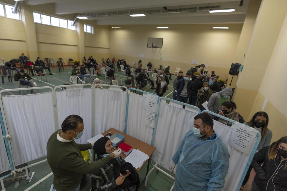 A health care worker takes a nasal swab sample from a Palestinian woman in a COVID-19 testing center, in the West Bank city of Ramallah on Wednesday. (AP)