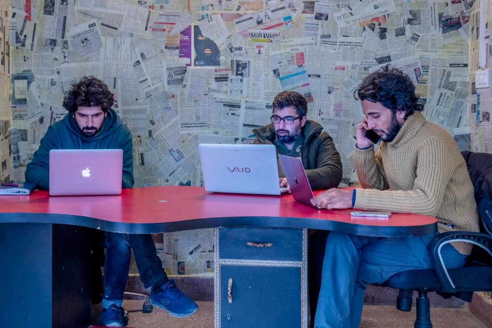 Fahad Shah, right, editor-in-chief of Kashmir Walla, works on his computer inside the newsroom at his office in Srinagar, Indian controlled Kashmir, Friday, Jan. 21, 2022. (AP)