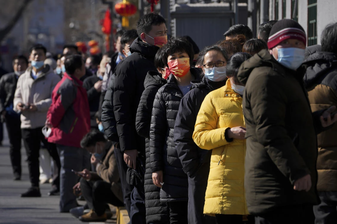 Residents wearing face masks to help protect from the coronavirus line up outside a COVID-19 test site in Beijing on Tuesday. (AP)