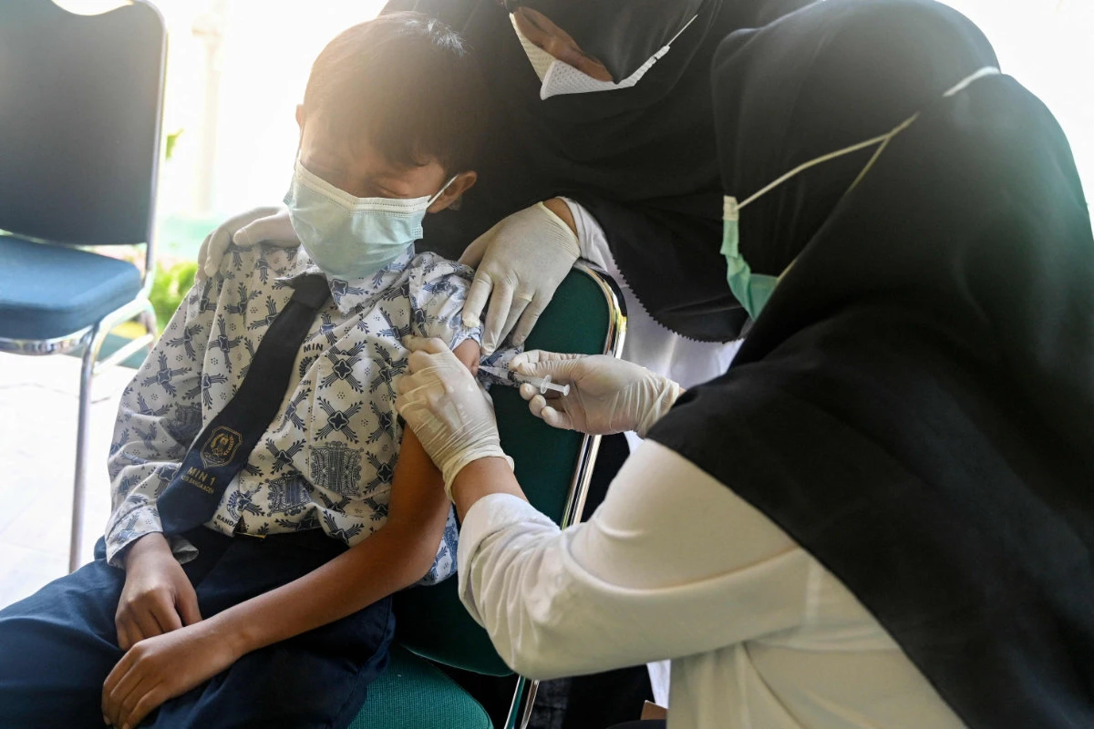 A student reacts as he gets a Sinovac vaccine shot against the COVID-19 coronavirus at an elementary school in Banda Aceh on February 9, 2022. (AFP)
