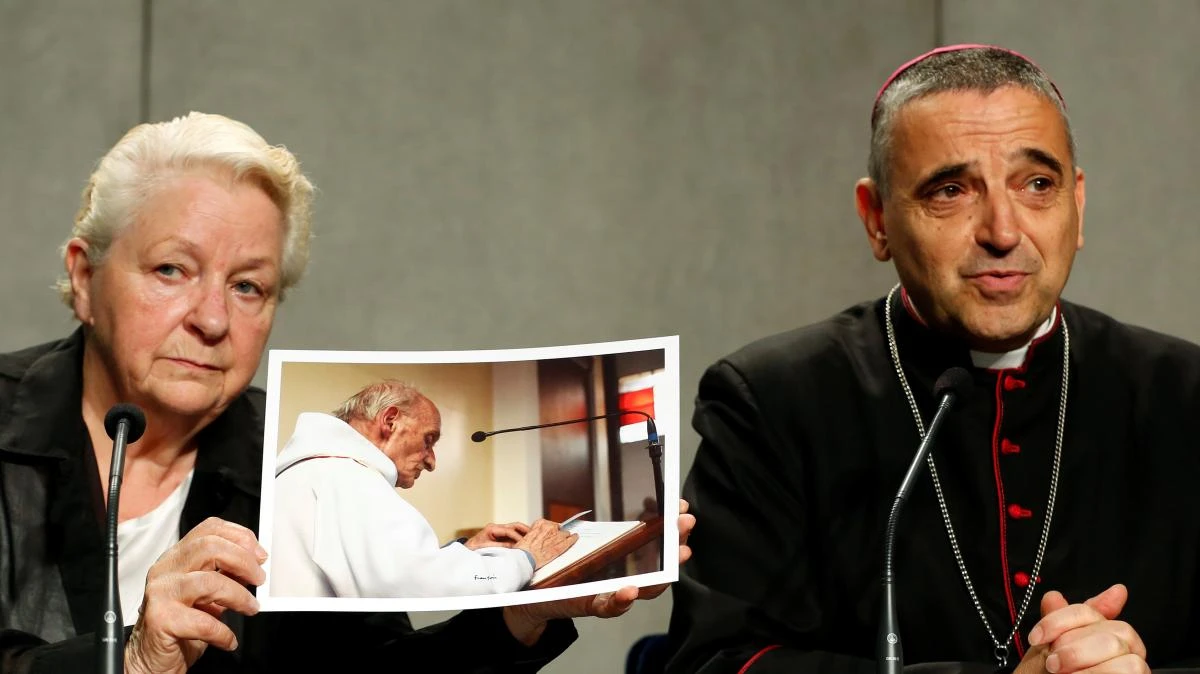 Roseline Hamel, with a picture of her brother, and Dominique Lebrun, the Archbishop of Rouen. (Reuters)
