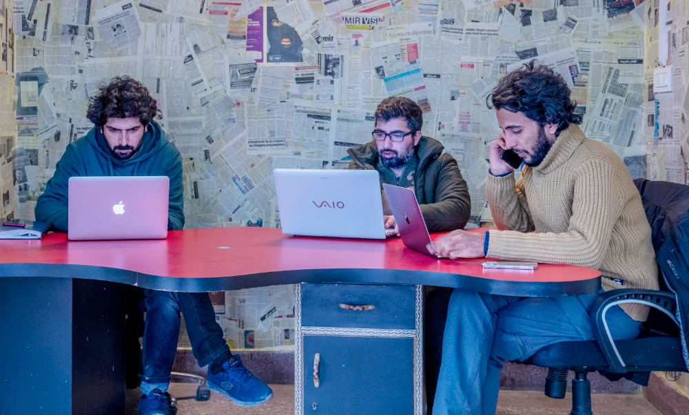 Fahad Shah, right, editor-in-chief of Kashmir Walla, works on his computer inside the newsroom at his office in Srinagar, Indian controlled Kashmir, Friday, Jan. 21, 2022. (AP)